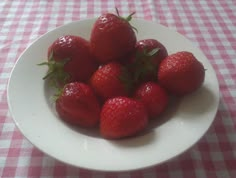 a white bowl filled with strawberries on top of a checkered table cloth