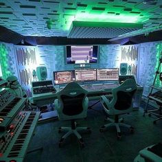 a recording studio with multiple monitors and keyboards on the wall, all lit up by green lights