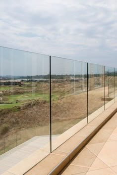 there is a long glass fence on the side of this building that overlooks a golf course