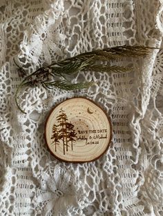 a wood slice with some pine trees on it and the words save the date printed on it