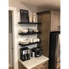 a kitchen with two shelves and coffee maker on the counter next to an open refrigerator