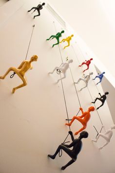 there are many toy figurines hanging on the wall with ropes attached to them