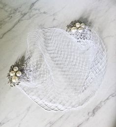 two pearls and mesh garters sitting on a marble counter top with white fabric