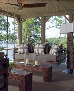 an image of a porch swing with pillows and candles on the end table next to it