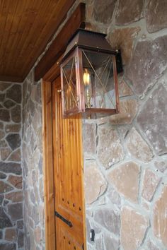 a light that is on the side of a stone wall next to a wooden door