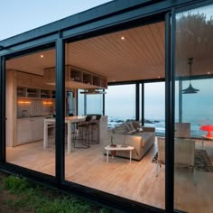 an open living room and dining area with glass walls on the outside, overlooking the ocean