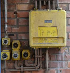 an electrical box on the side of a brick wall next to some pipes and fittings