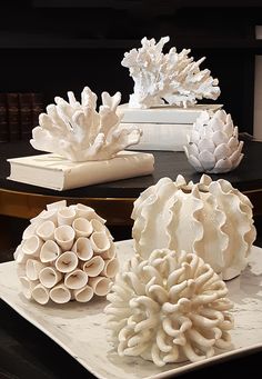 three white vases sitting on top of a table next to books and other decorative items