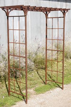 two metal trelliss sitting next to each other in front of a building with grass