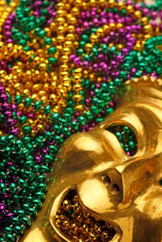 a close up of a gold mask with beads on the ground in front of it