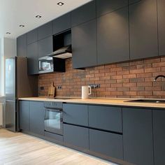 an empty kitchen with grey cabinets and wood flooring is pictured in this image from the front view