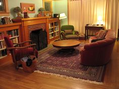 a living room filled with furniture and a fire place next to a book shelf on top of a hard wood floor