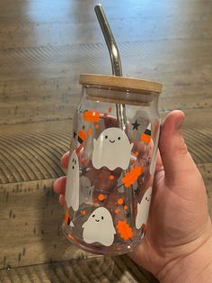 a hand holding a glass jar with halloween decorations on it