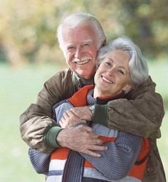 an older couple embracing each other in the park