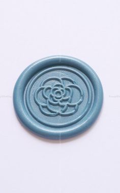 a blue wax stamp with a flower on the center and an interlocked circle in the middle