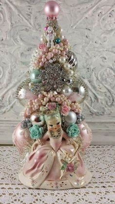 a small christmas tree with ornaments on it's sides and an angel figurine in the middle