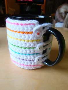 a crocheted coffee cup holder is sitting on a table