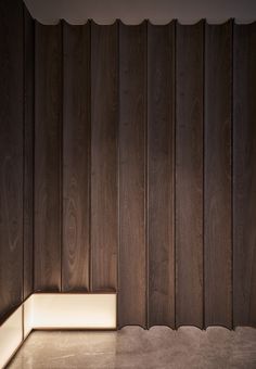 an empty room with wood paneling on the wall and light in the corner at the end