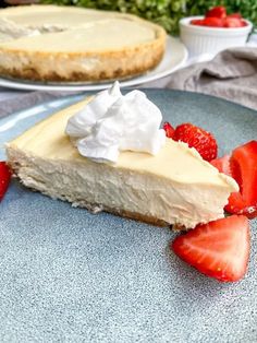 a slice of cheesecake with whipped cream and strawberries on a plate next to another pie