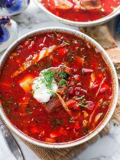 two bowls of tomato soup with sour cream and bread on the side for garnish