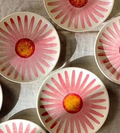 four pink and white plates with flowers painted on the inside are arranged in a pattern