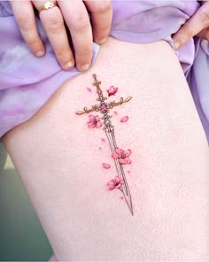 a woman's thigh with pink flowers and a cross tattoo on her lower back