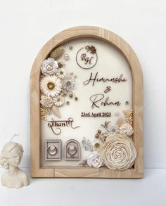 a wooden frame with flowers on it next to a figurine