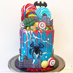 a spiderman themed birthday cake with splattered icing and candies on top