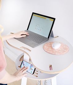 a woman is using her cell phone and laptop at the table with an ipad on it