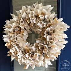 a wreath made out of book pages sitting on top of a blue front door frame