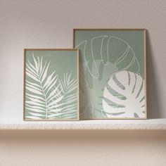 two framed tropical prints on a mantle in a living room or bedroom, one is green and the other is white