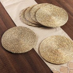 three woven placemats sitting on top of a wooden table next to each other