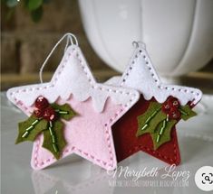 two felt christmas decorations hanging from strings on a table