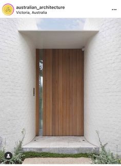 the front door is open and there are plants growing in the ground below it on either side of the doorway