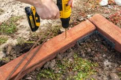 a man is using a drill to fix a piece of wood that has been placed on the ground