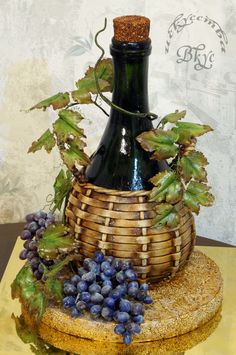 a wine bottle sitting on top of a wooden basket filled with grapes and green leaves