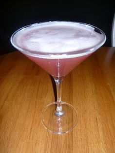 a pink drink sitting on top of a wooden table