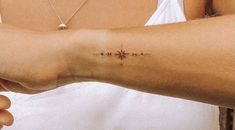 a woman's arm with a small cross tattoo on the left side of her arm