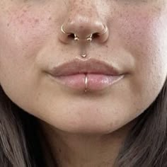 a woman with freckles and piercings on her nose