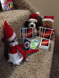 the elf is sitting on the stairs next to his toys and playing with cards in front of him