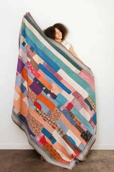 a woman wrapped up in a multicolored blanket