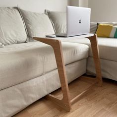 a laptop on a wooden stand in front of a couch