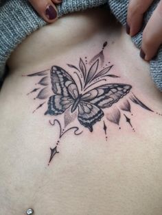 a woman's stomach with a butterfly tattoo on it