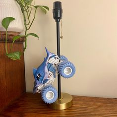 a toy car on a stand next to a potted plant