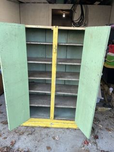 an old yellow and green metal cabinet with shelves in the middle, sitting on dirt ground