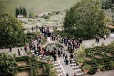 an aerial view of a wedding ceremony in the middle of a garden with hedges and potted trees