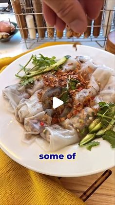 a white plate topped with dumplings and veggies on top of a wooden table