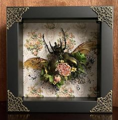 an insect is mounted in a frame with flowers