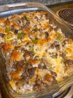 a casserole dish with meat, cheese and vegetables in it on top of a stove