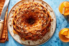 a bundt cake on a plate with oranges and silverware next to it